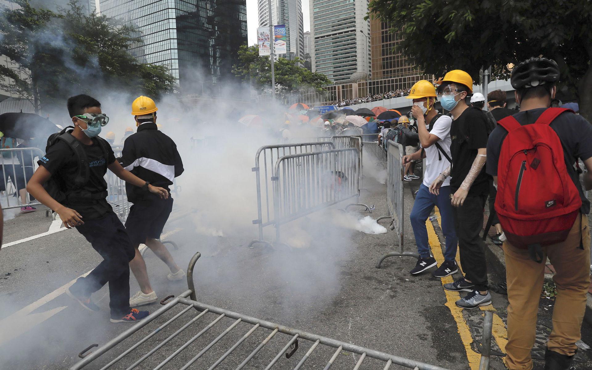 Protesters react to tear gas during a large protest near the Legislative Council in Hong Kong, Wednesday, June 12, 2019. Hong Kong police have used tear gas and high-pressure hoses against thousands of protesters opposing a highly controversial extradition bill outside government headquarters.  (AP Photo/Kin Cheung)