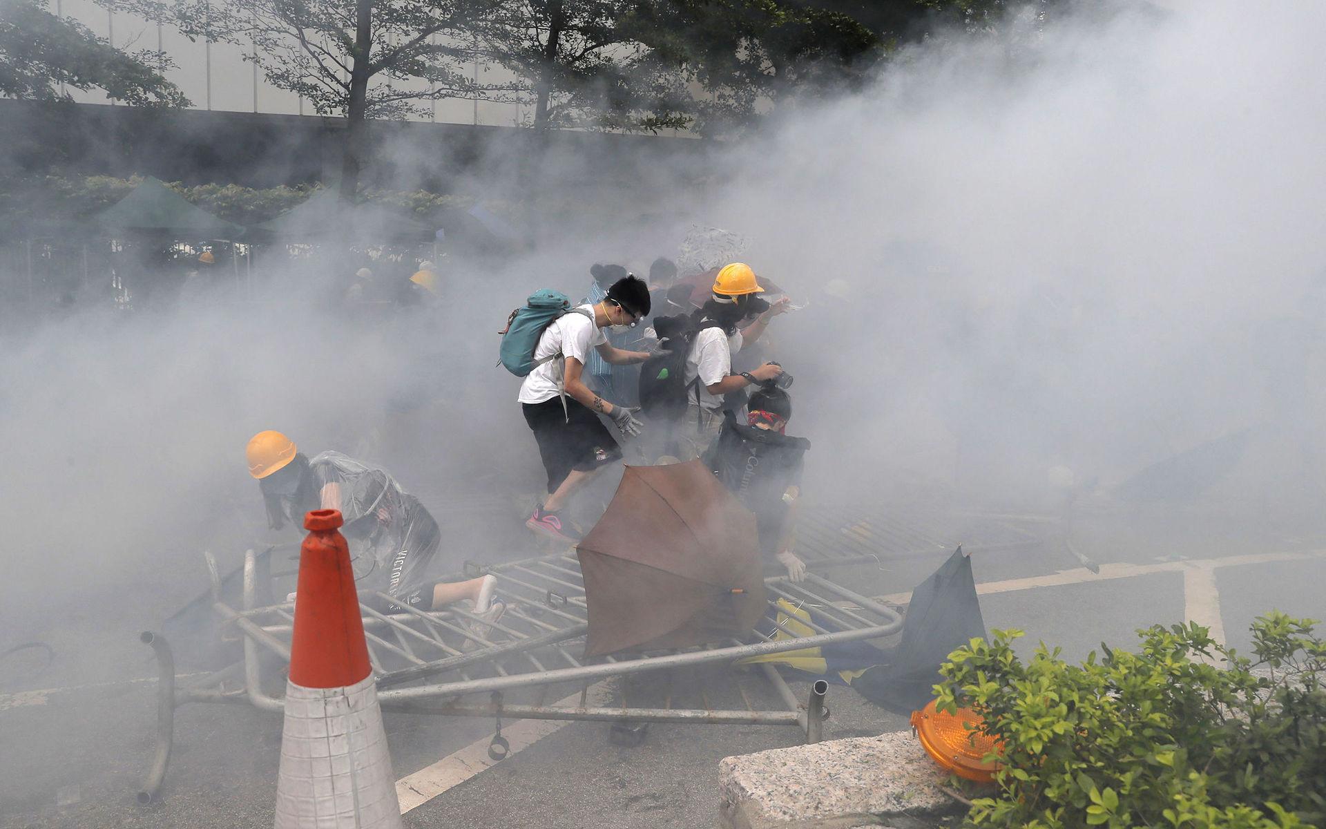 In this June 12, 2019, file photo, protesters react to a cloud of tear gas near the Legislative Council in Hong Kong. (AP Photo/Kin Cheung, File)