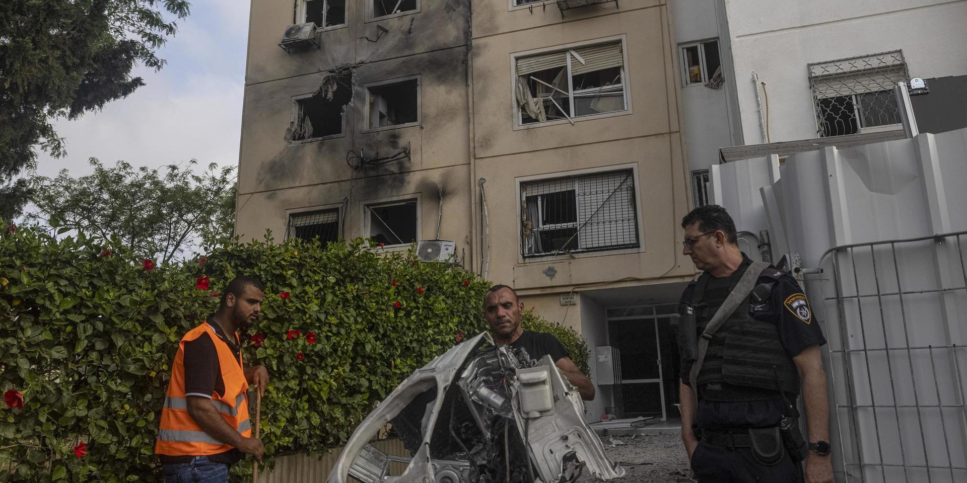 Förstörda hushållsapparater bärs ut från det träffade huset i israeliska Ashkelon.