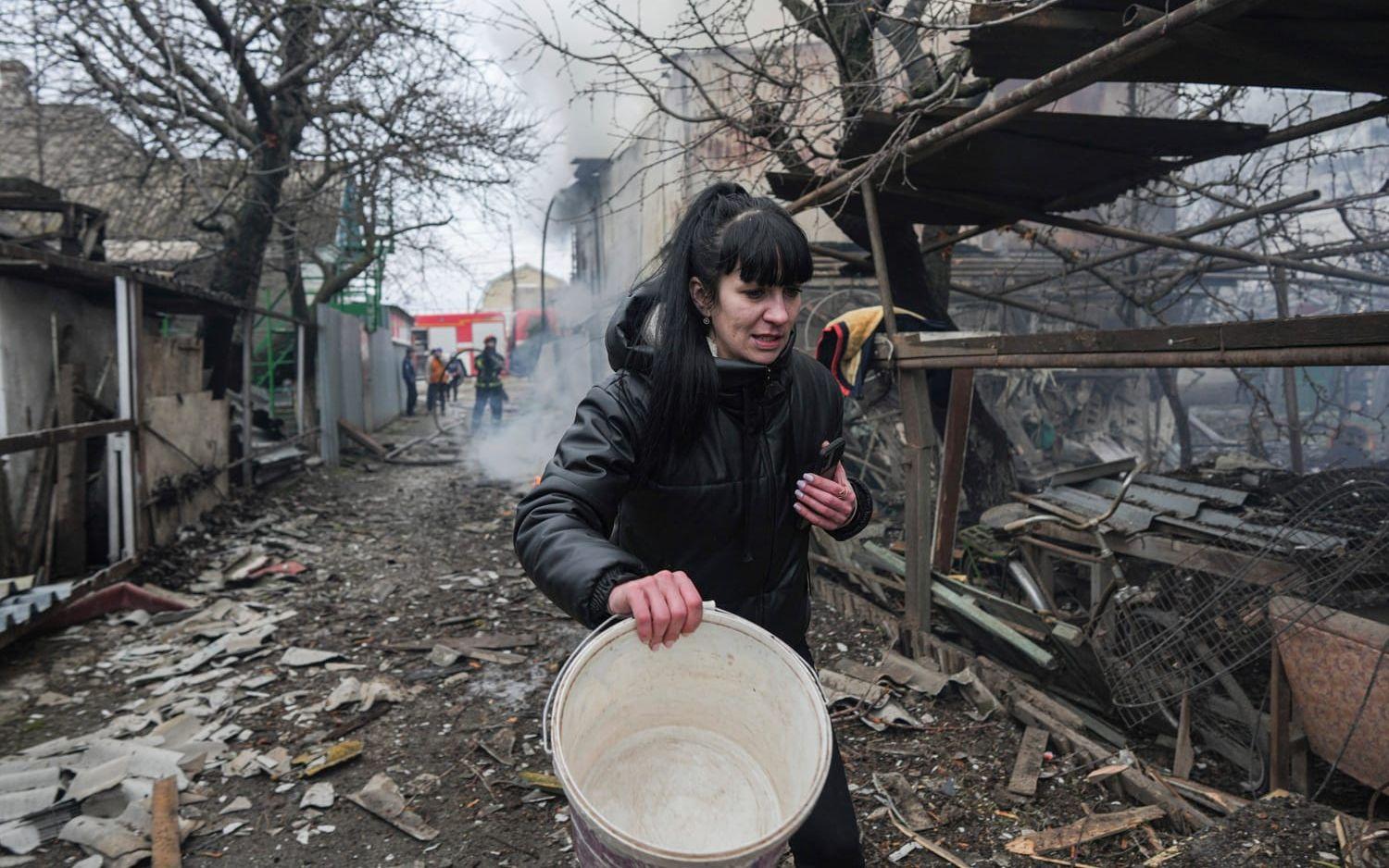 En kvinna går bland spillror av kvarteret på en gata i Mariupol.