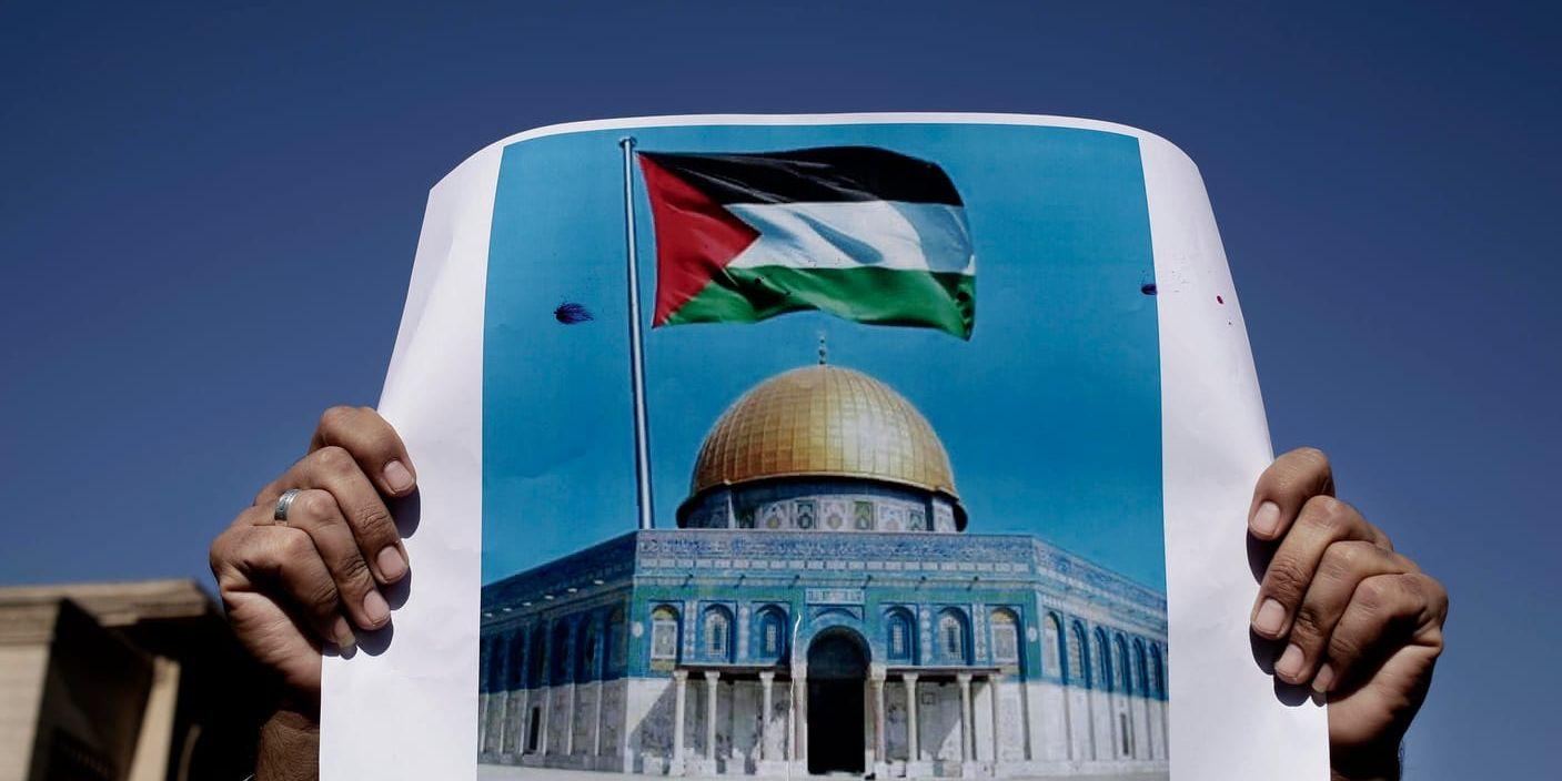 En man håller en bild av den palestinska flaggan och al-Aqsa-moskén under en demonstration mot USA:s beslut i Kairo.