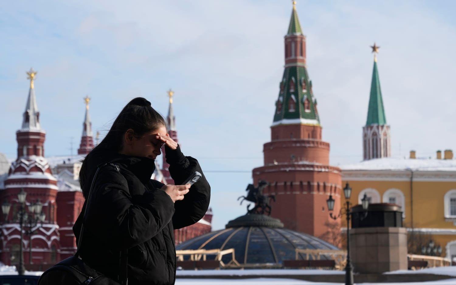 En kvinna tittar på sin telefon samtidigt som hon promenerar i Moskva. Arkivbild.