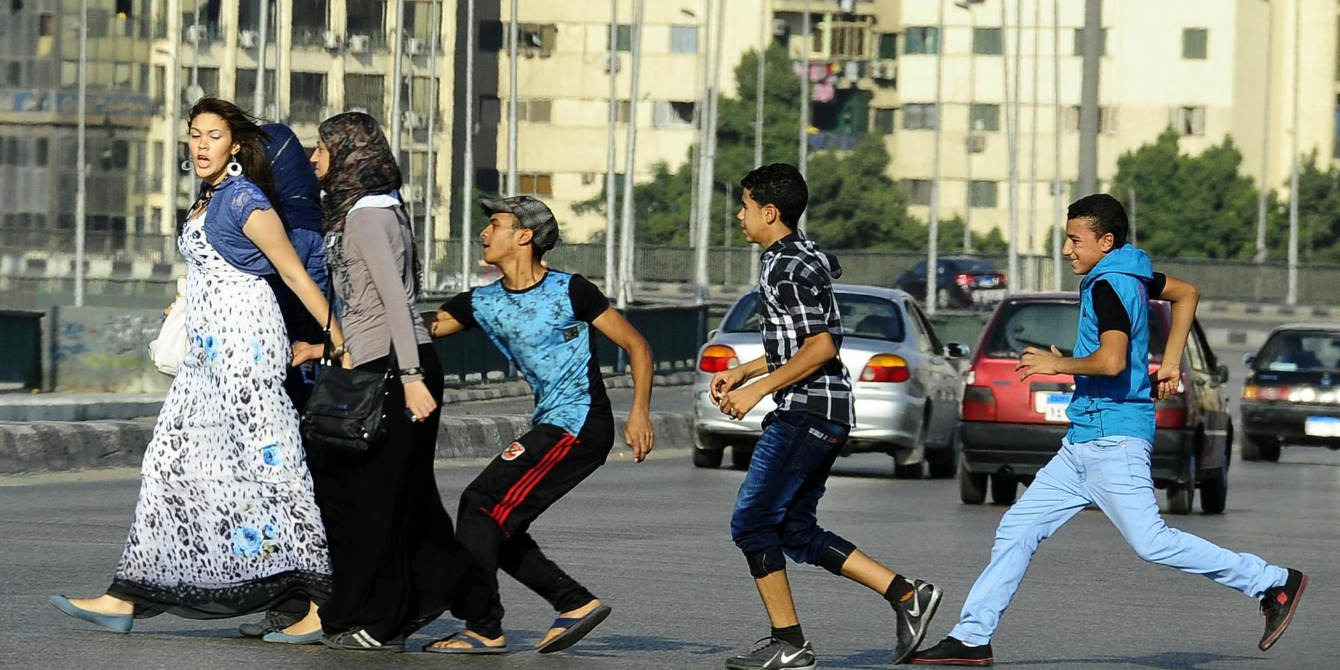 En ung man, med sina vänner i släptåg, tafsar på en kvinna då hon går över en gata i Kairo. Arkivbild.