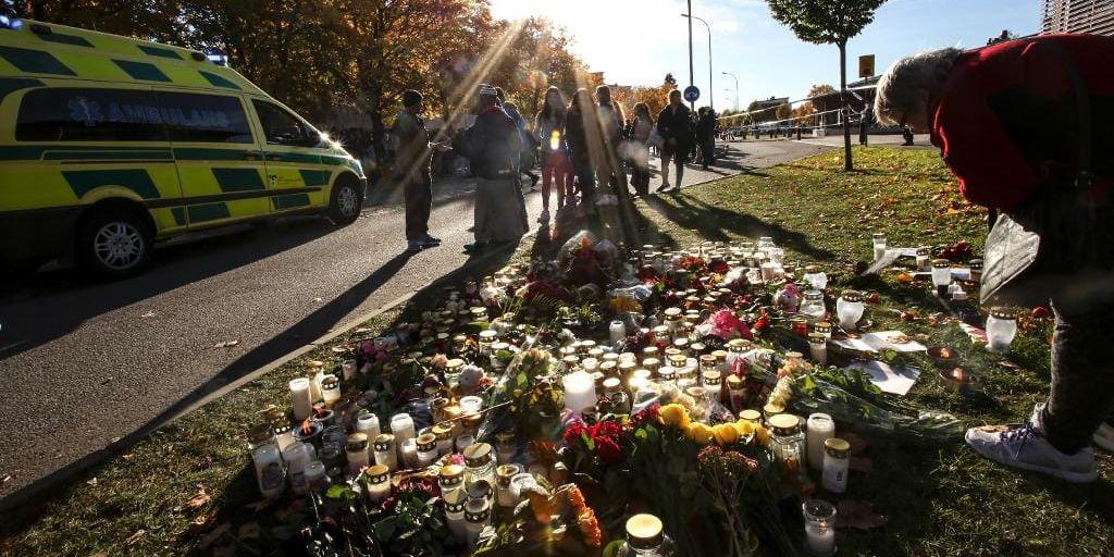 En kvinna lägger ner blommor utanför skolan Kronan i Trollhättan på fredagen, dagen efter attacken som krävde tre människors liv.