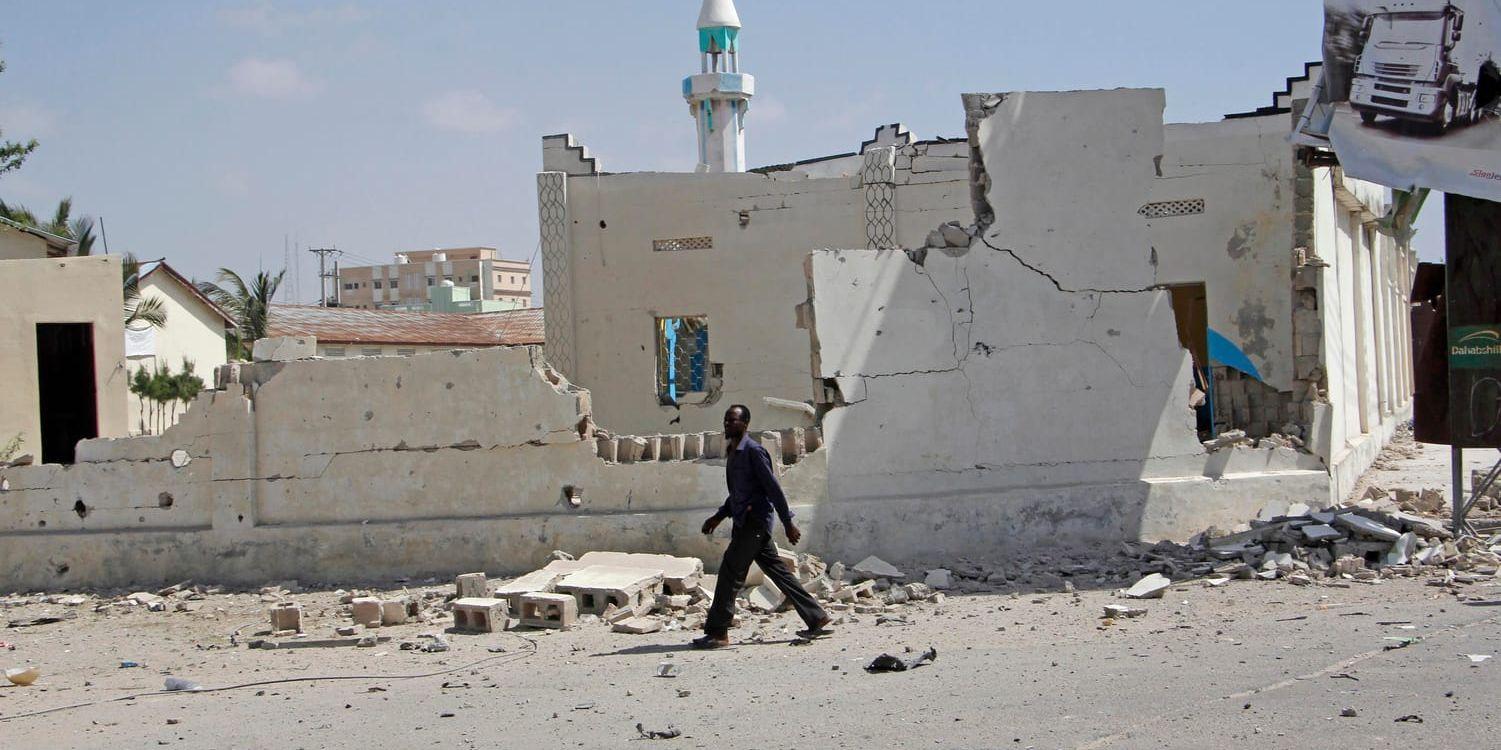 En man går förbi en förstörd byggnad efter lördagens bilbombsattacker i Somalias huvudstad Mogadishu.
