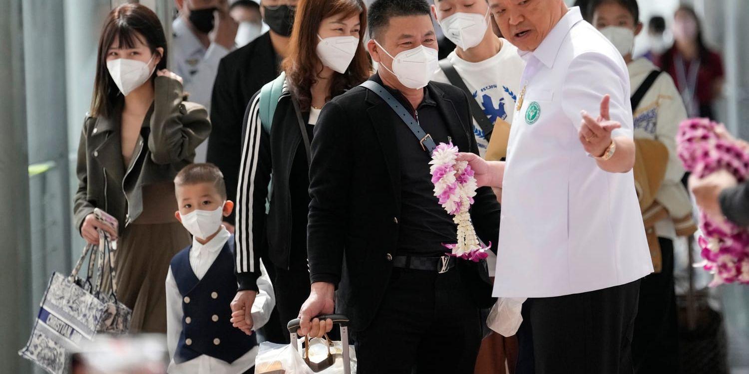 Thailands hälsominister Anutin Charnvirakul hälsar kinesiska besökare välkomna på flygplatsen i Bangkok. Landet har nu beslutat att slopa kraven på att man ska kunna uppvisa vaccinationsbevis. 