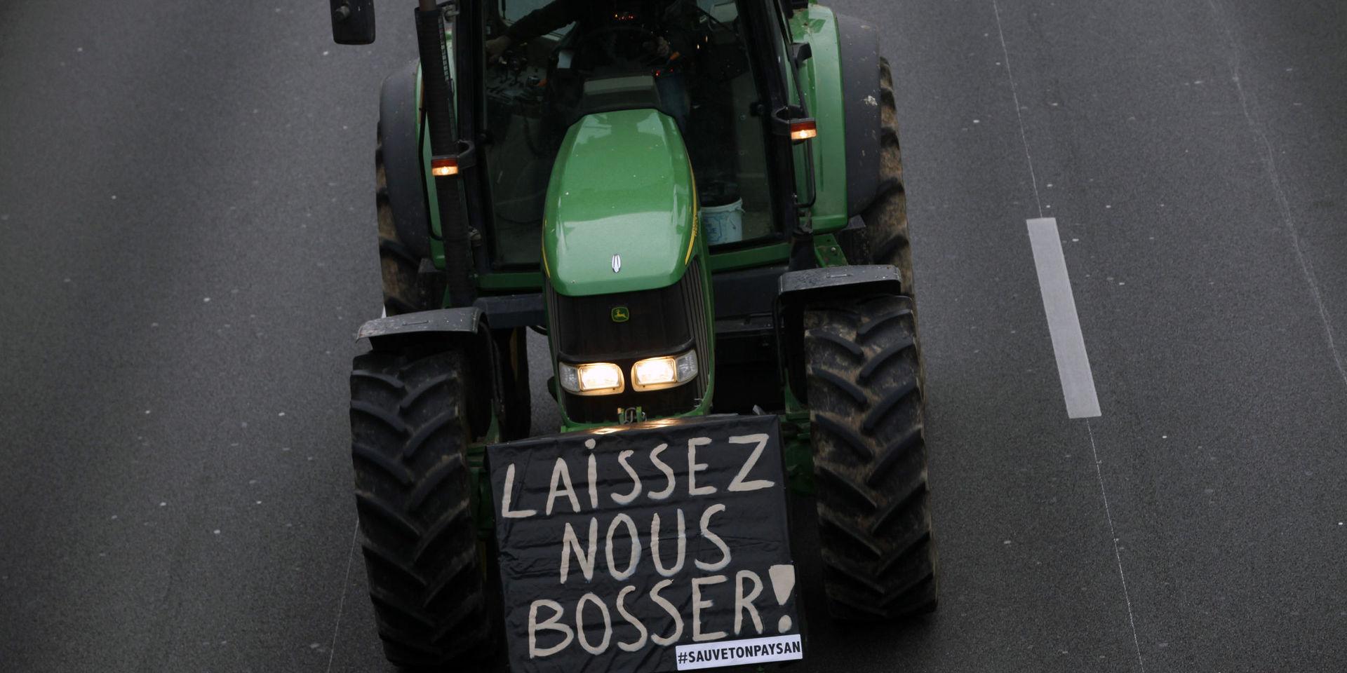 &quot;Låt oss jobba&quot; står det på en av traktorerna som kör på ringvägen kring Paris.