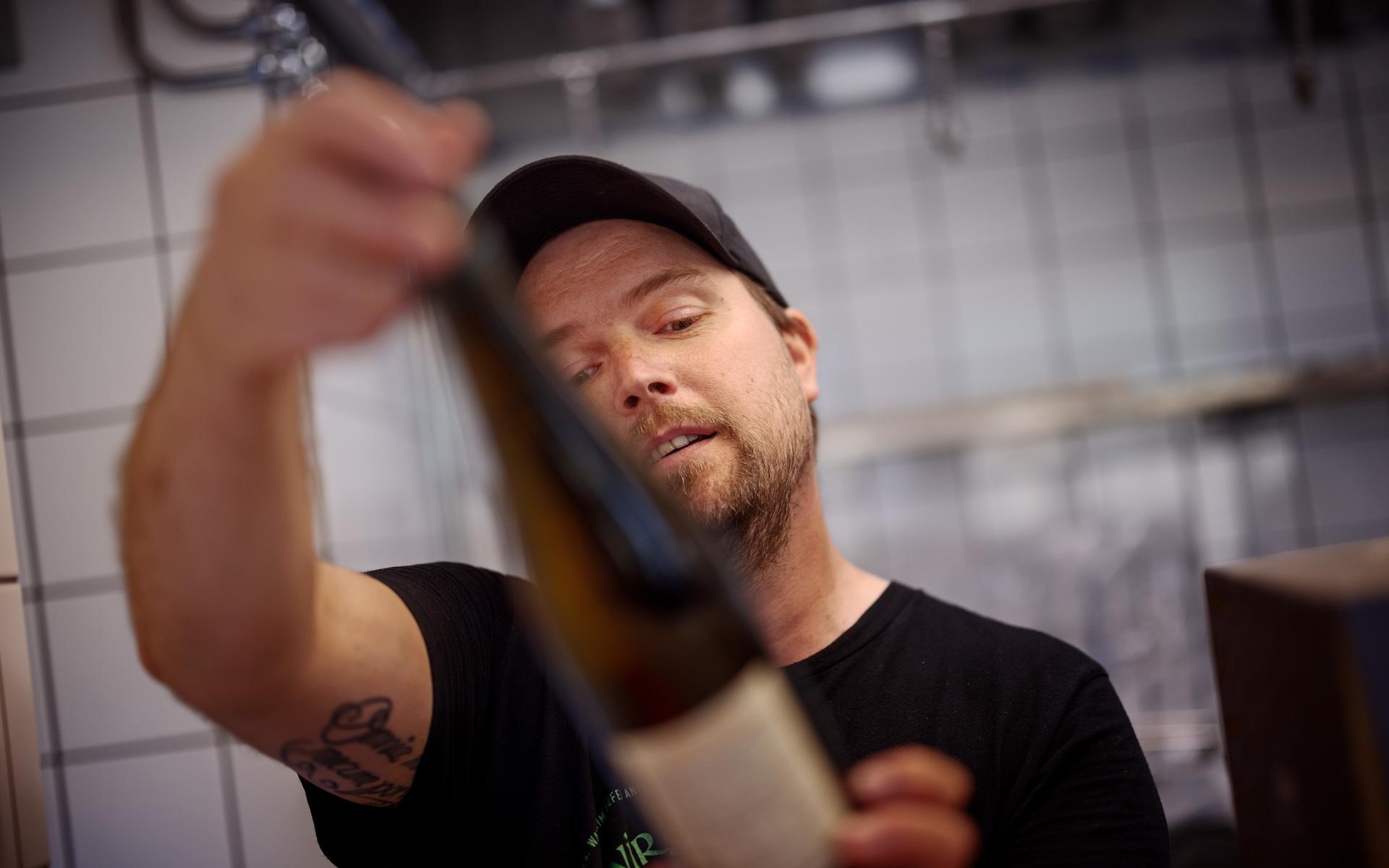 Mikael Andersson inspekterar en av vinflaskorna från Östeuropa. Mikael är också den som tagit fram menyn. 