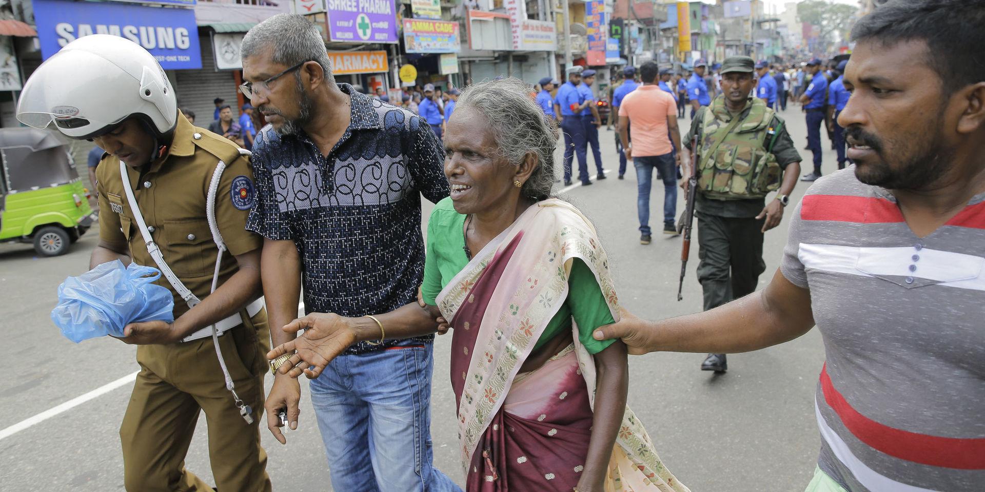 En äldre kvinna får hjälp efter explosionen i S.t Anthonys kyrka i Colombo. Samtidigt ska det ha exploderat på ytterligare två kyrkor och tre hotell i landet.