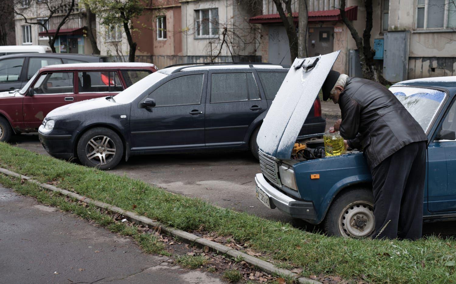 En man fyller på med vinterspolarvätska i sin sovjetiska bil av modellen Lada. En klassiker som blir allt ovanligare i landet.