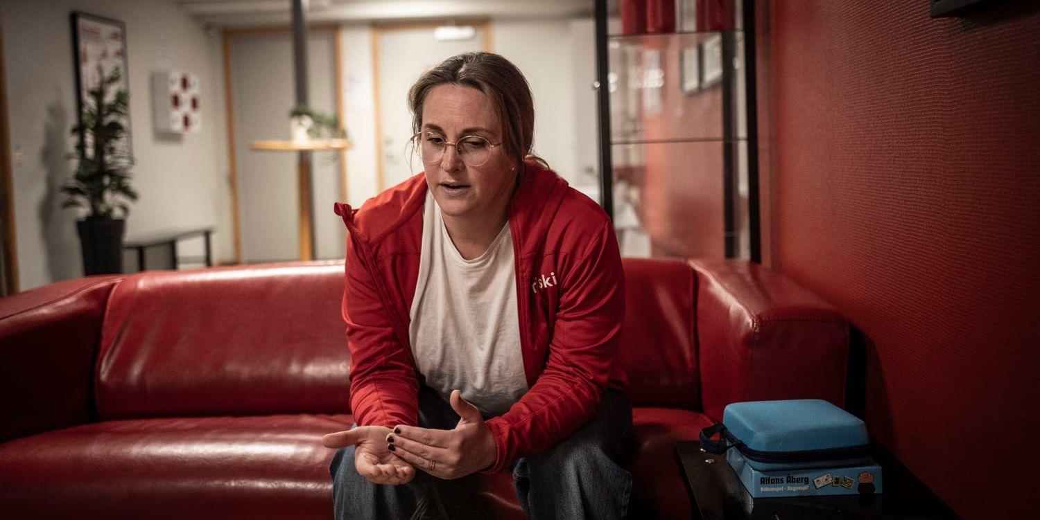 En kvinna sitter i en soffa och gestikulerar.