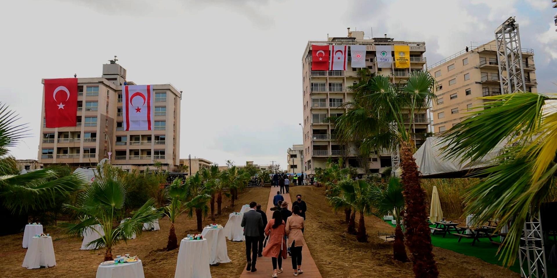 Folk promenerar förbi övergivna byggnader med turkiska och turkcypriotiska flaggor inför den turkiske presidenten Recep Tayyip Erdogans besök vid det nyöppnade strandområdet i den omstridda stadsdelen Varosha.