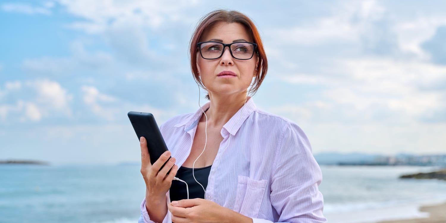 Arkivbild på en kvinna som lyssnar på stranden.