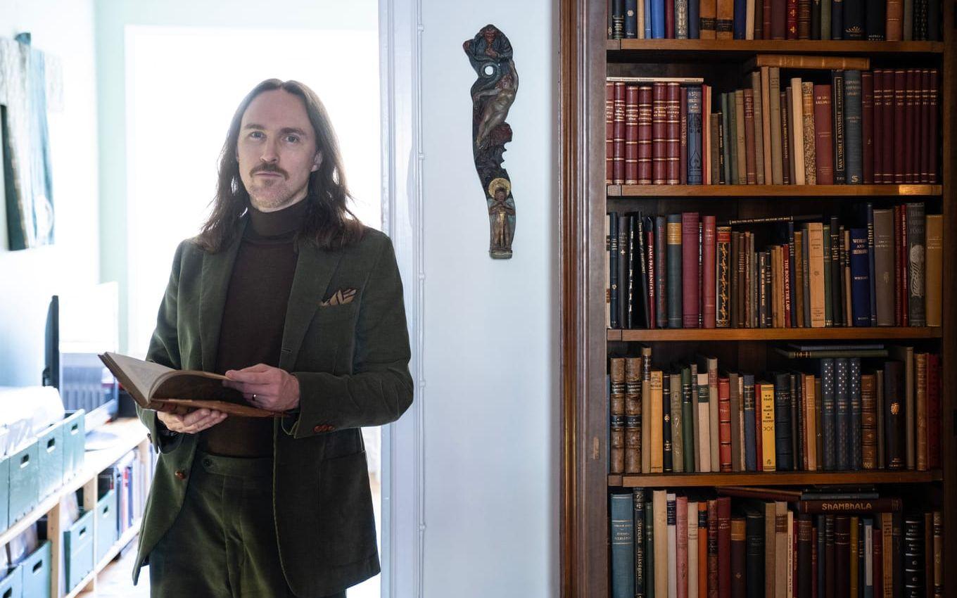 Per Faxneld hemma i lägenheten i Stockholm, där ett stort bibliotek samsas med masker från olika världsdelar. 