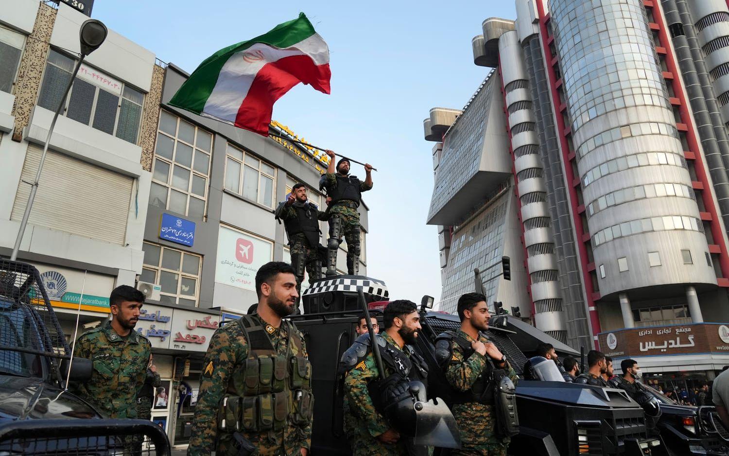 Kravallpolis firar med den iranska flaggan efter Irans seger mot Wales i gruppspelet. Efter förlusten mot USA och uttåget ur VM var det mindre glada miner från regimen.