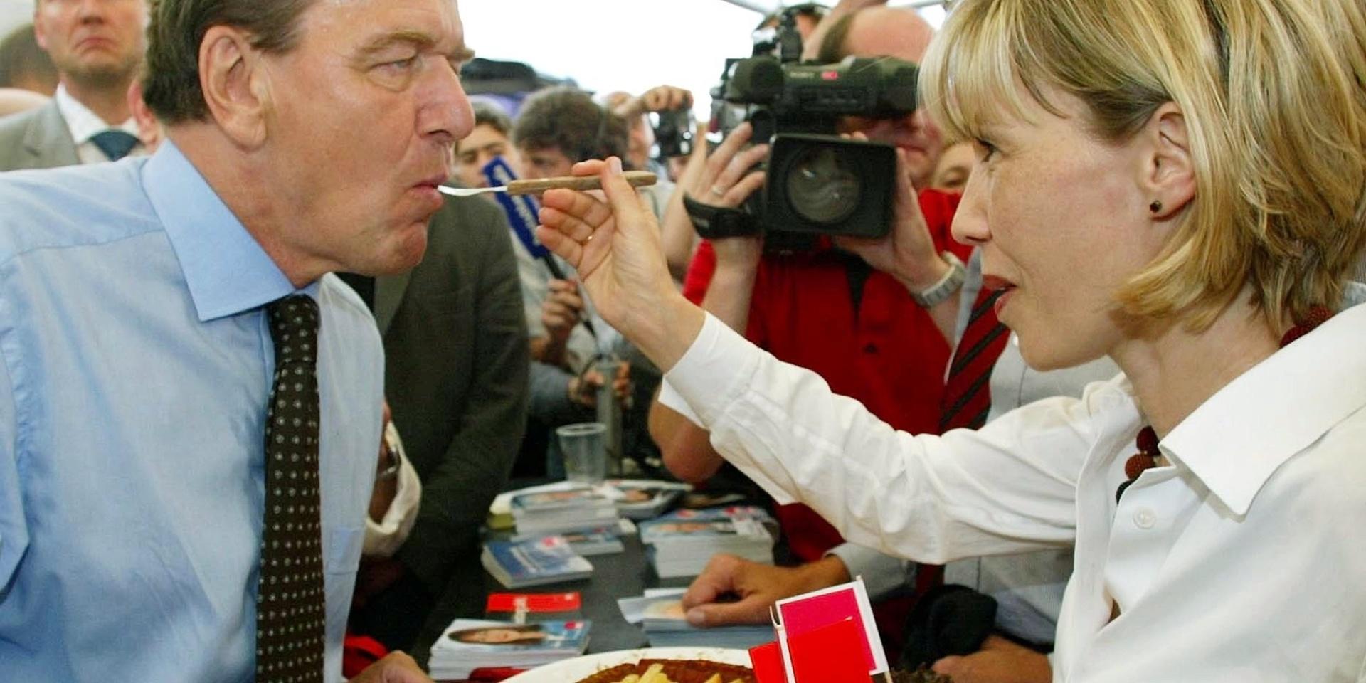 Gerhard Schröder hymlar inte med sin förkärlek till currykorv. Här matas han av sin dåvarande fru, Doris Schröder-Kopf, vid en gatufestival 2002. Schröder var vid tidpunkten tysk förbundskansler.