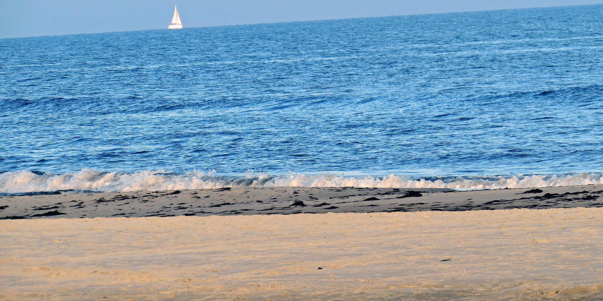 En ensam segelbåt på synranden, den rör sig knappt. Här finns de farliga sandrevlarna. 