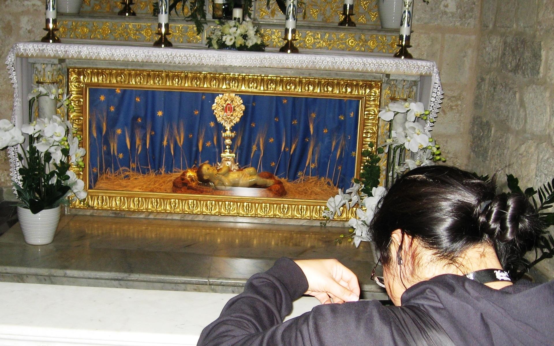 En pilgrim knäböjer i S:ta Catharinakyrkan i Betlehem framför den nyanlända reliken – en träflisa ur Jesu krubba.