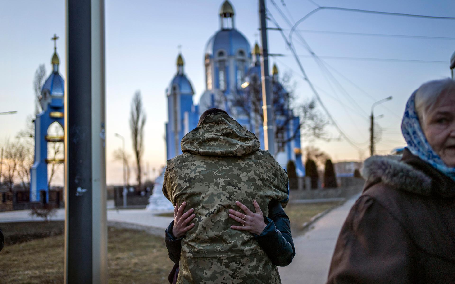En soldat omfamnar en anhörig, som nu ska lämna Ukraina. 