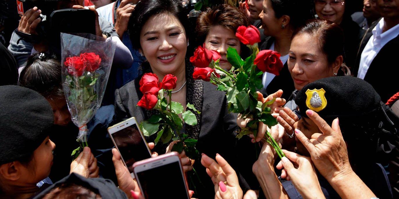 Thailands tidigare premiärminister Yingluck Shinawatra får blommor av anhängare efter att ha hållit sitt slutanförande i rättegången.