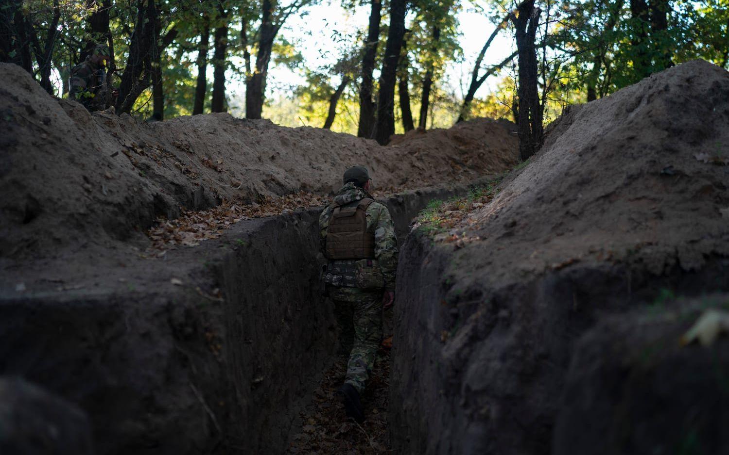 Ukrainska soldater inspekterar en skyttegrav grävd av ryska soldater i ett återtaget område i Chersonregionen. Bild från den 12 oktober.