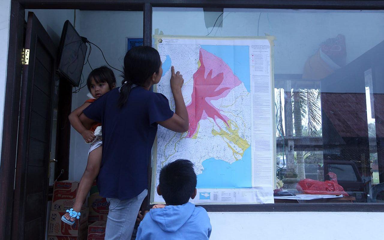 En kvinna och hennes barn studerar en karta som visar farozonerna på Bali om Agung får ett utbrott. Bilden är tagen den 23 september. FOTO: Firdia Lisnawati/AP
