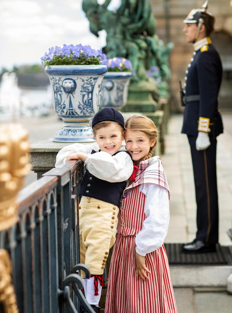 Syskonen prinsessan Estelle och prins Oscar gör högvakten sällskap framför Kungliga Slottet.