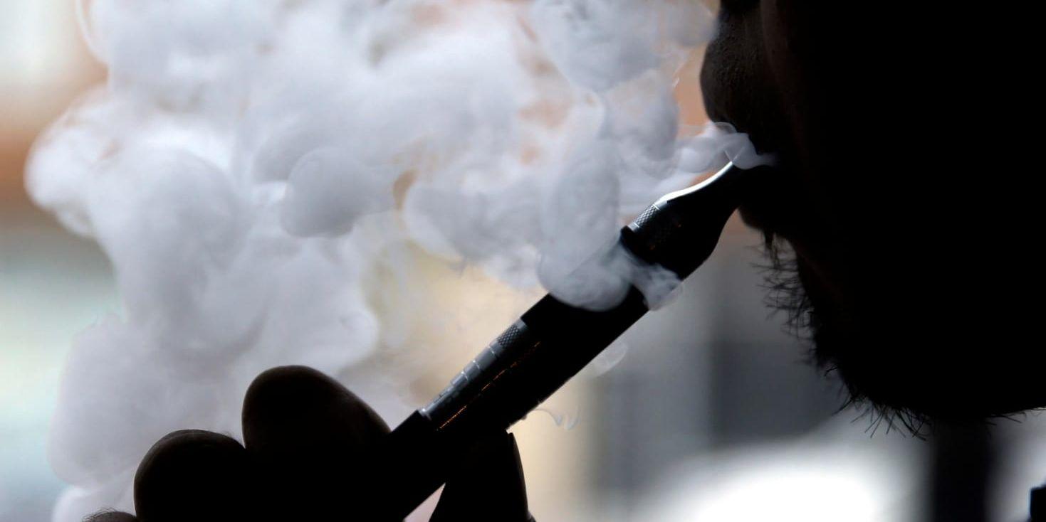 En man blåser ut rök från en e-cigarett. Arkivbild.