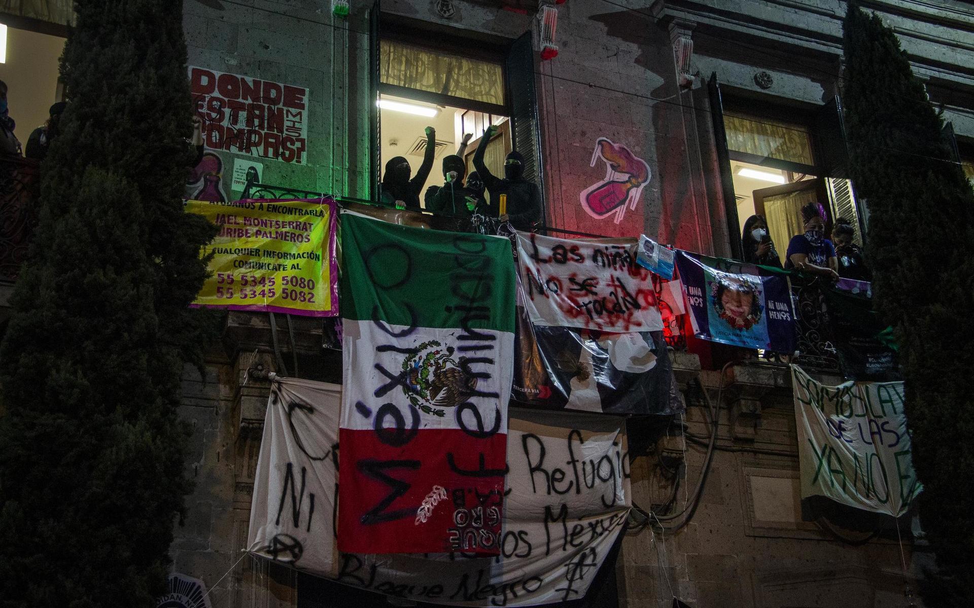 Aktivister har hängt upp en flagga med texten Mexiko kvinnomördare från myndighetsbyggnaden som de har ockuperat.