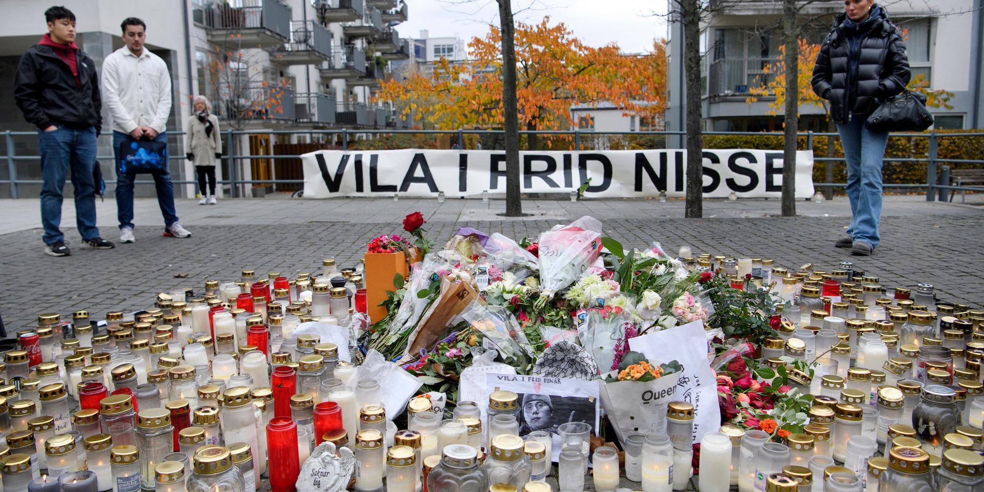 Blommor och ljus i närheten av platsen i Hammarby sjöstad i Stockholm där Nils Grönberg, mer känd som rapparen Einár, sköts till döds för en vecka sedan.