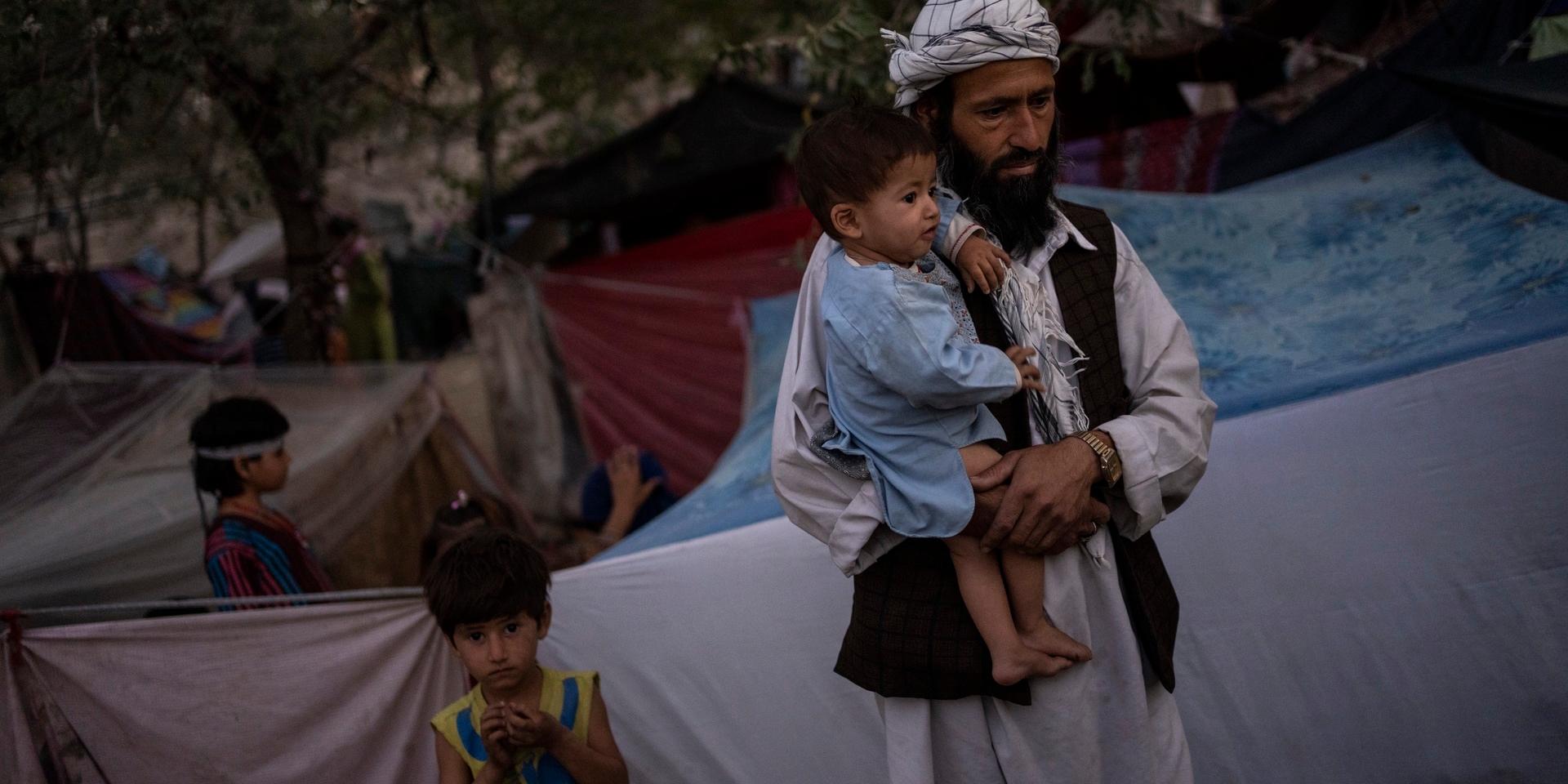 En afghansk barnfamilj, väntandes på matdonationer i ett flyktingläger i Kabul under måndagen.