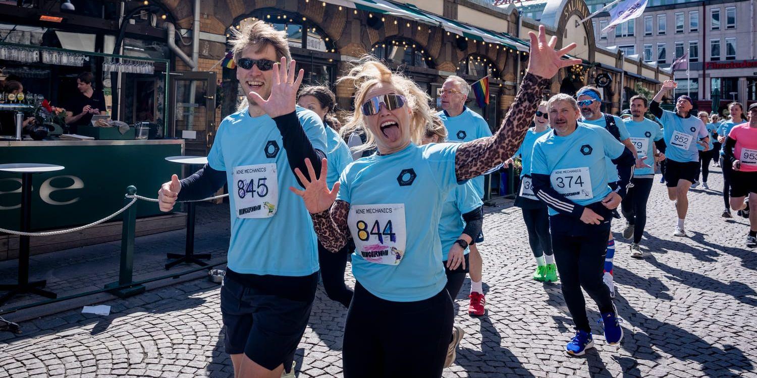 Två av Vingelrundans glada deltagare i förgrunden joggar vidare och vinkar efter sin femte provsmakning utanför Saluhallen.