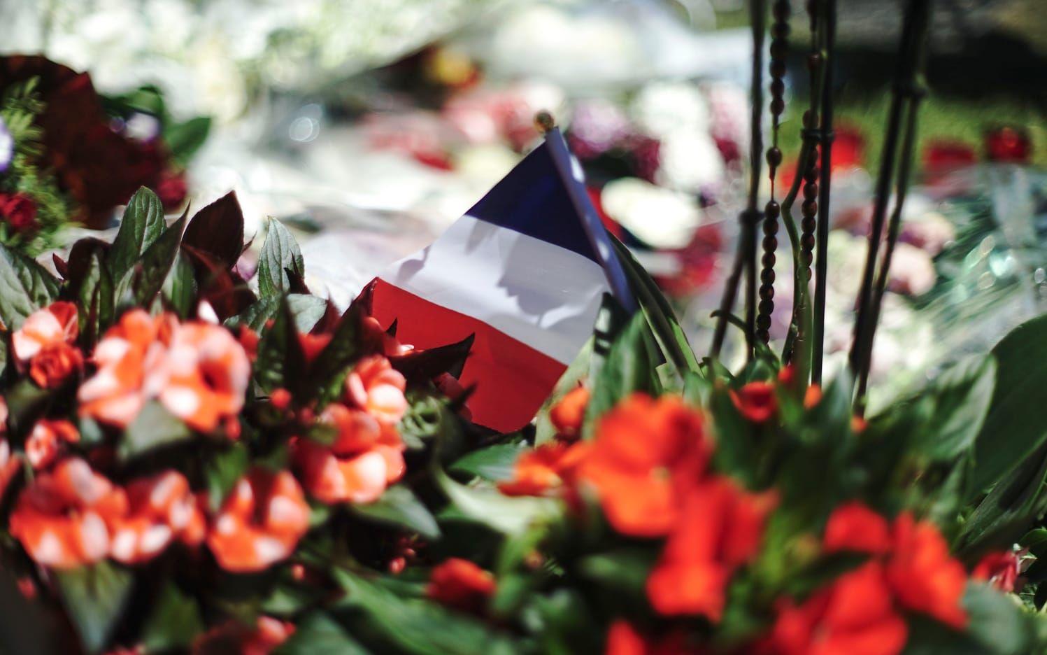 Blommor och en fransk flagga är kvarlämnade på gatan där de fruktansvärda scenerna utspelade sig. Foto: TT