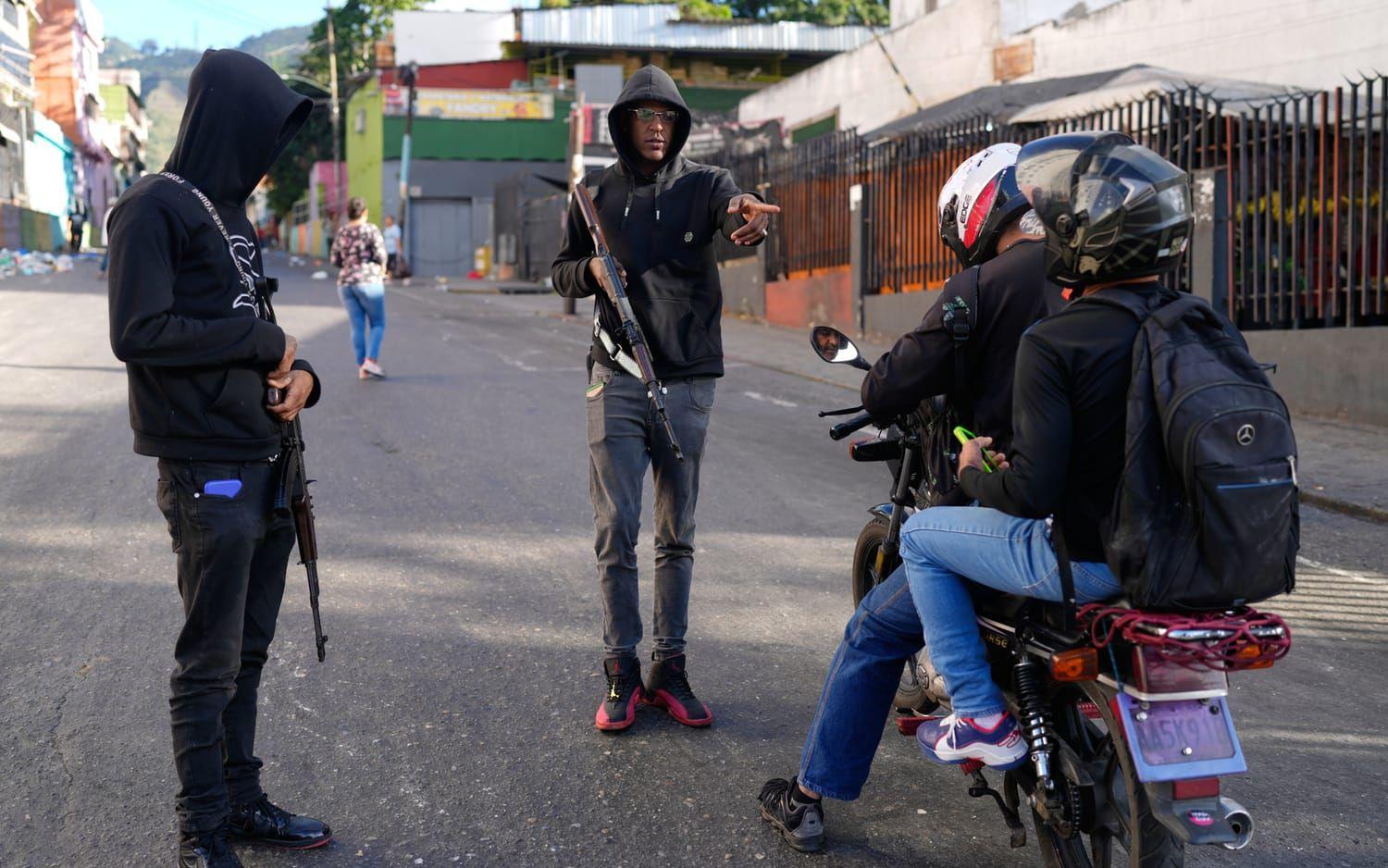 Regimtrogna personer med vapen stoppar två personer på en motorcykel i Caracas på söndagen.
