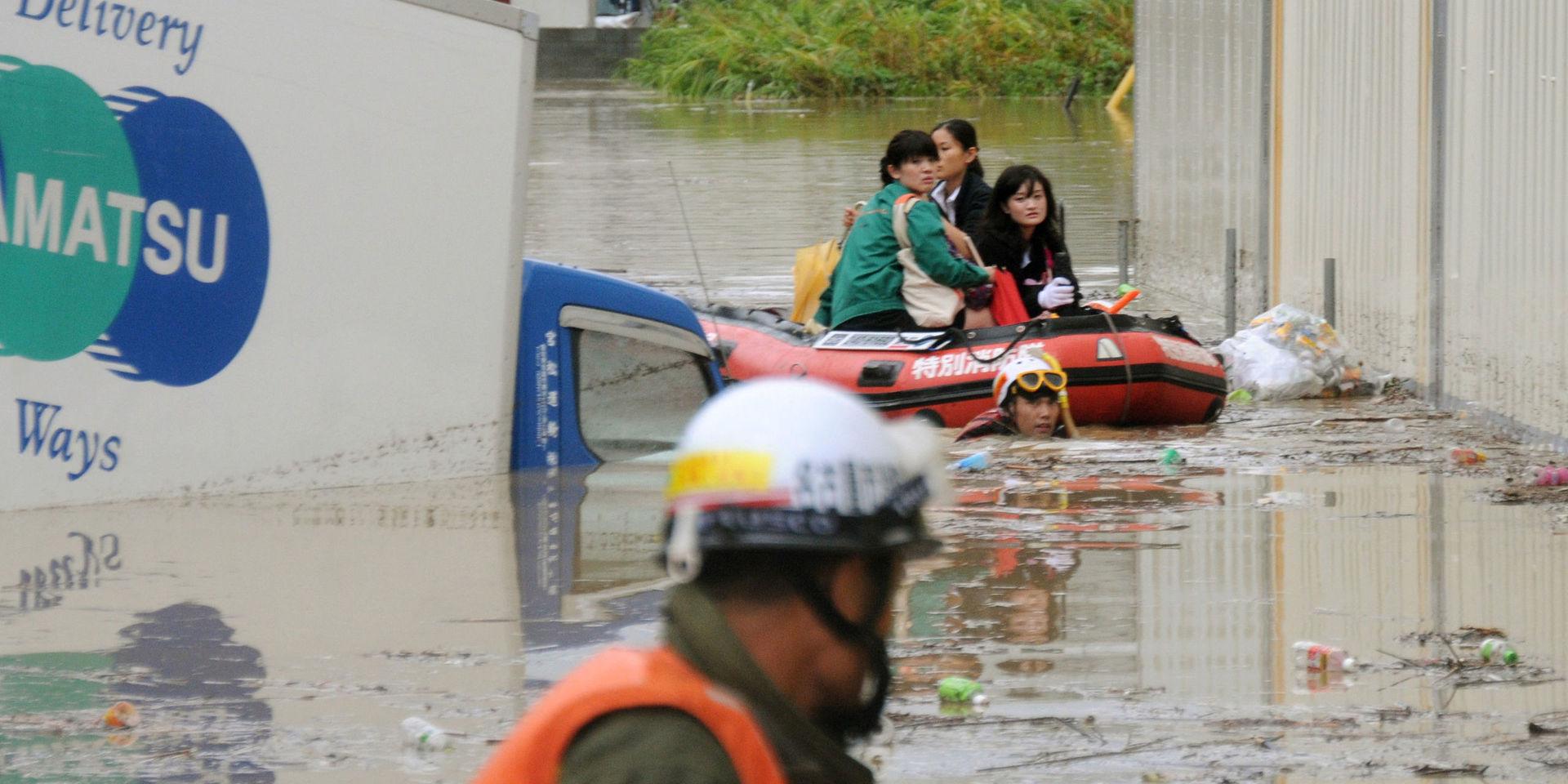 Några anställda tvingas lämna sitt översvämmade kontor i båt i Nagoya i centrala Japan, den 20 september.