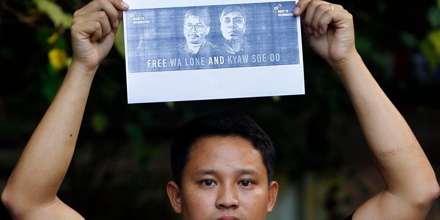 En kollega håller upp en bild på de två fängslade reportrarna i Myanmars huvudstad Naypyidaw häromdagen.