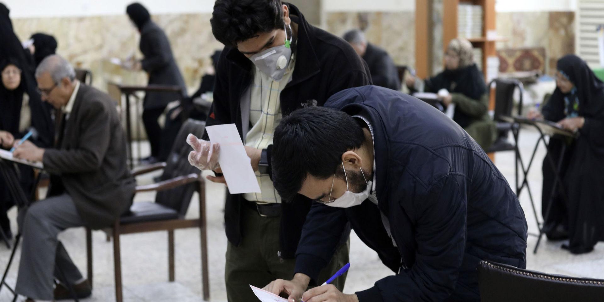En del iranier har på sig munskydd i vallokalerna där de lägger sina röster i parlamentsvalet.