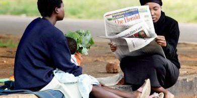 Två zimbabwiska kvinnor med gårdagens The Herald.