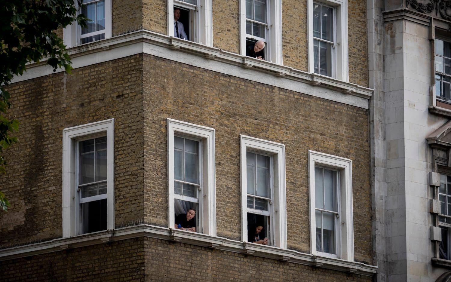 Längs Whitehall ligger många regeringsdepartement. Åskådarna tittar ut genom sina kontorsfönster när kistan närmar sig.