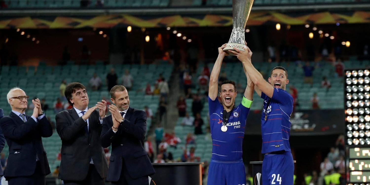 Chelsea Cesar Azpilicueta och Gary Cahill lyfter Europa League-pokalen. I bakgrunden tittar några enstaka åskådare på.