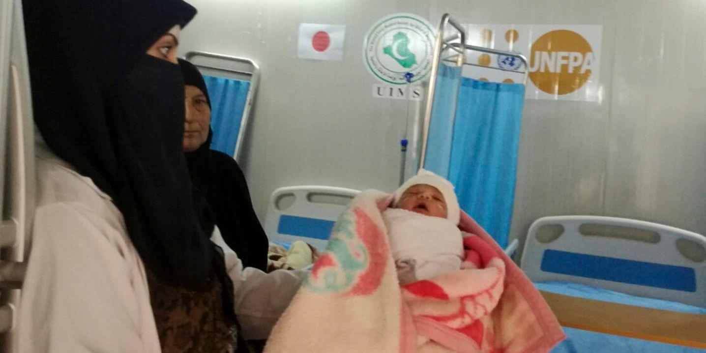 Barnmorskor håller upp ett nyförlöst barn på UNFPA:s förlossningsklinik på fältsjukhuset i Mosul.