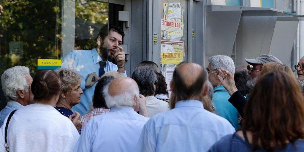 Pensionärer väntar otåligt utanför en bank i Aten i hopp om att den ska öppna för att betala ut pensioner.