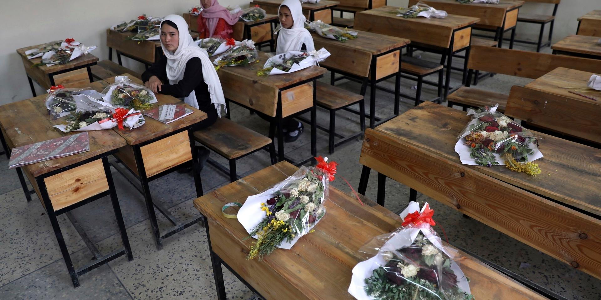 Skolflickor i Kabul. Klasskamrater som dött i flyganfall hedras med buketter. Flickornas framtid beror på talibanernas riktning, enligt experter. Arkivbild.