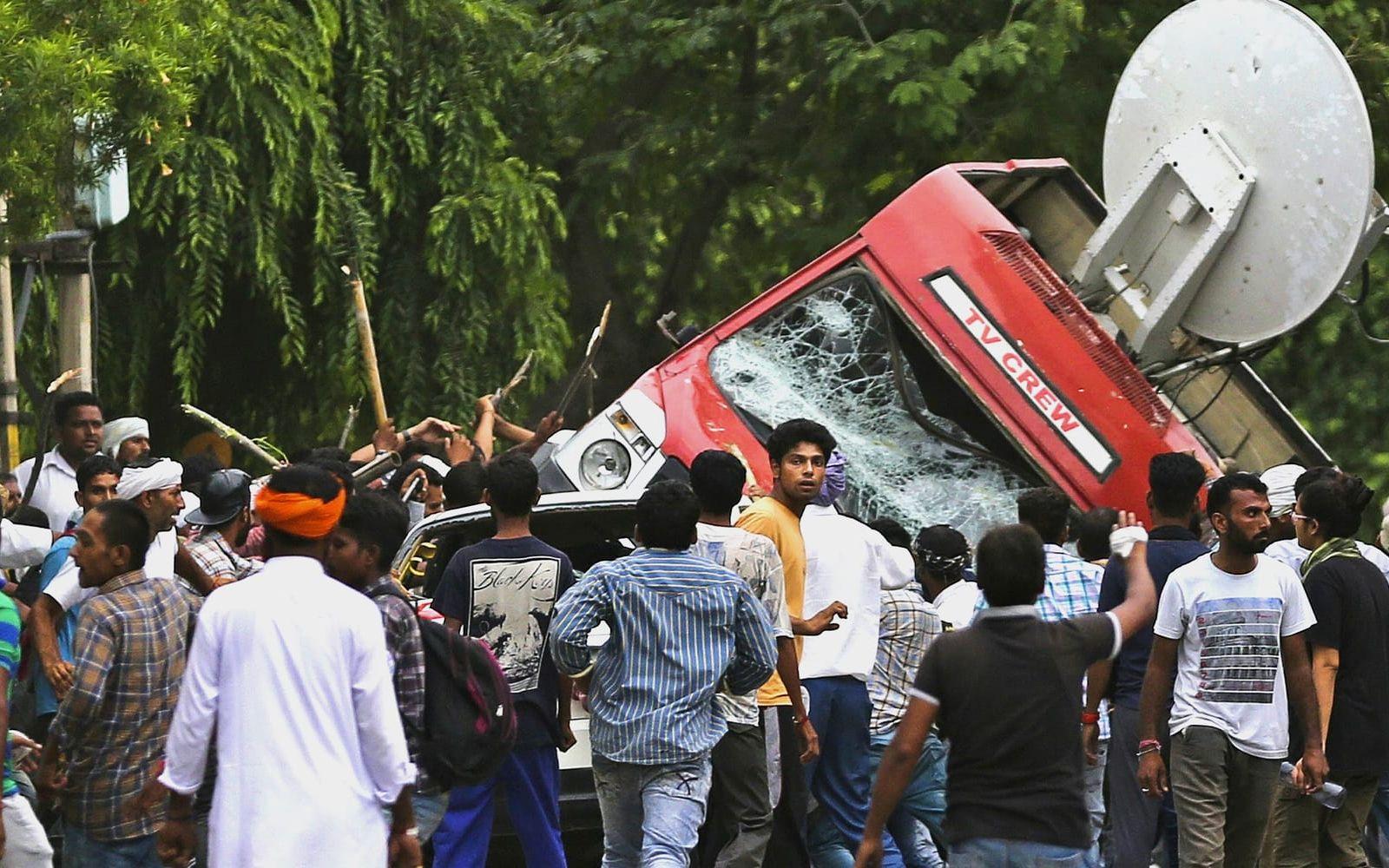 En mobb av guruns anhängare gav sig på en lokal-tv bil. Det rapporteras om flera attacker om journalister på plats.
