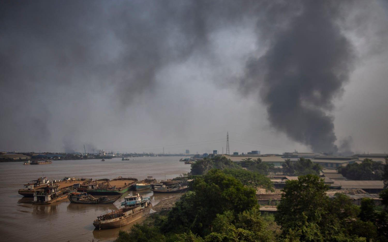 Svart rök sprider sig från industribyggnaderna i Hlaing Tharyar i Yangon. Under protesterna plundrades vissa fabriker och sattes sedan i brand.