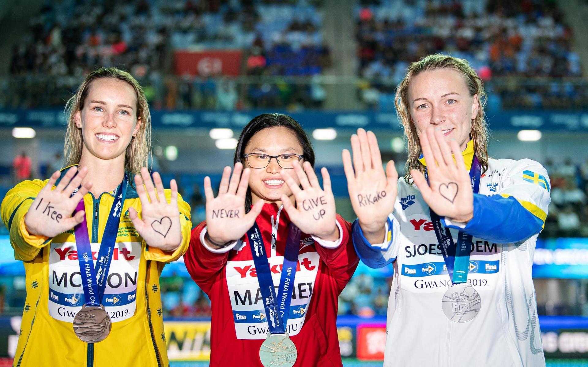 Emma McKeon (australien, brons), Margaret MacNeil (Kanada, guld) och Sarah Sjöström visar upp sitt stöd till den japanska simstjärnan.