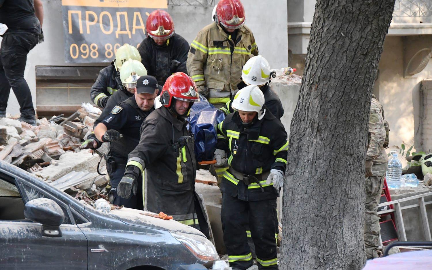 Räddningsarbetare bär ut en kropp från ett lägenhetshus som attackerats i en rysk attack mot Lviv.