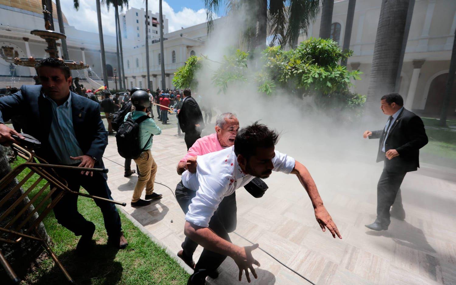 Människor flyr vid parlamentet efter att oppositionspolitiker slogs blodiga av regeringstrogna våldsverkare . Bild: TT