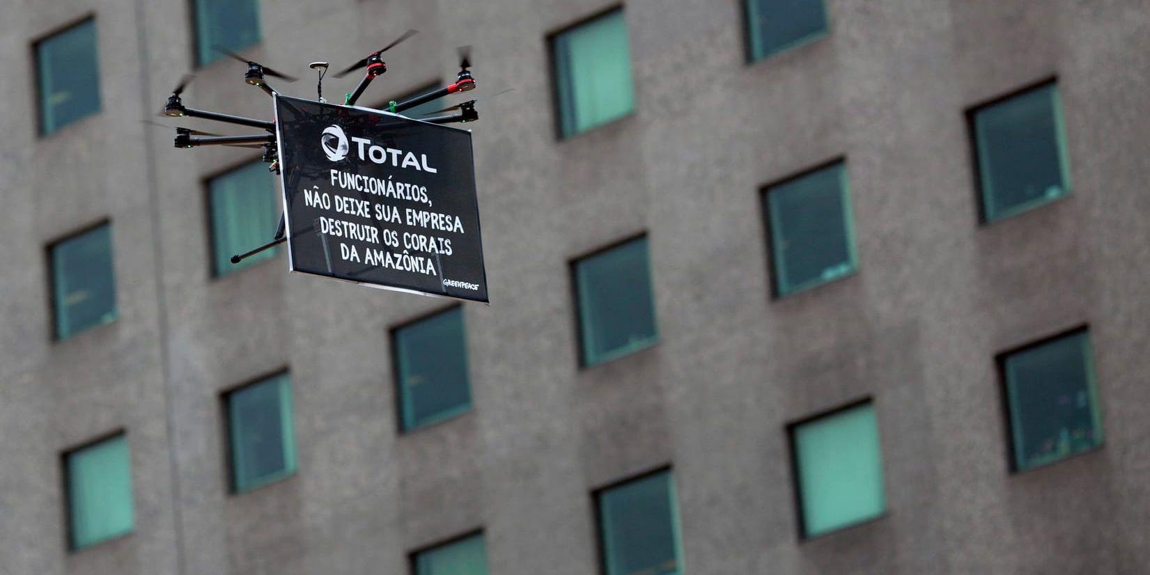 Protesterna mot oljeplanerna är många i Brasilien. Här håller en drönare under en aktion förra året upp en banderoll vid Totals lokaler i Rio de Janeiro, med texten: "Total-anställda, låt inte ert företag förstöra Amazonas koraller".