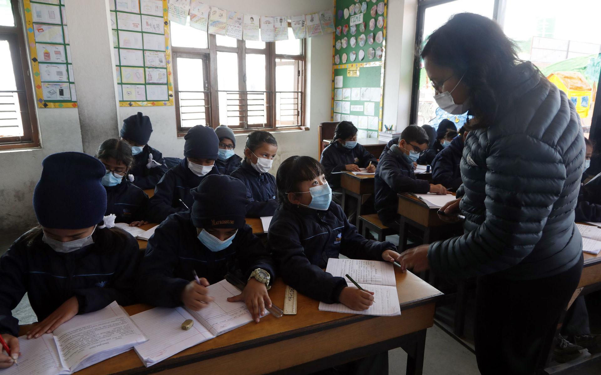 Skolbarn i Nepal bär skyddsmasker i klassrummet för att skydda sig mot viruset.